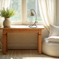 The champagne mist colored indoor solar chime sitting on a wooden table in front of  window 