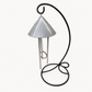 An indoor pewter colored solar wind chime featuring a textured silver metal cone-shaped top and three silver hanging rods, supported by a curved black metal stand