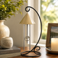 Decorative lamp with wind chimes on a table next to a candle and photo frame.