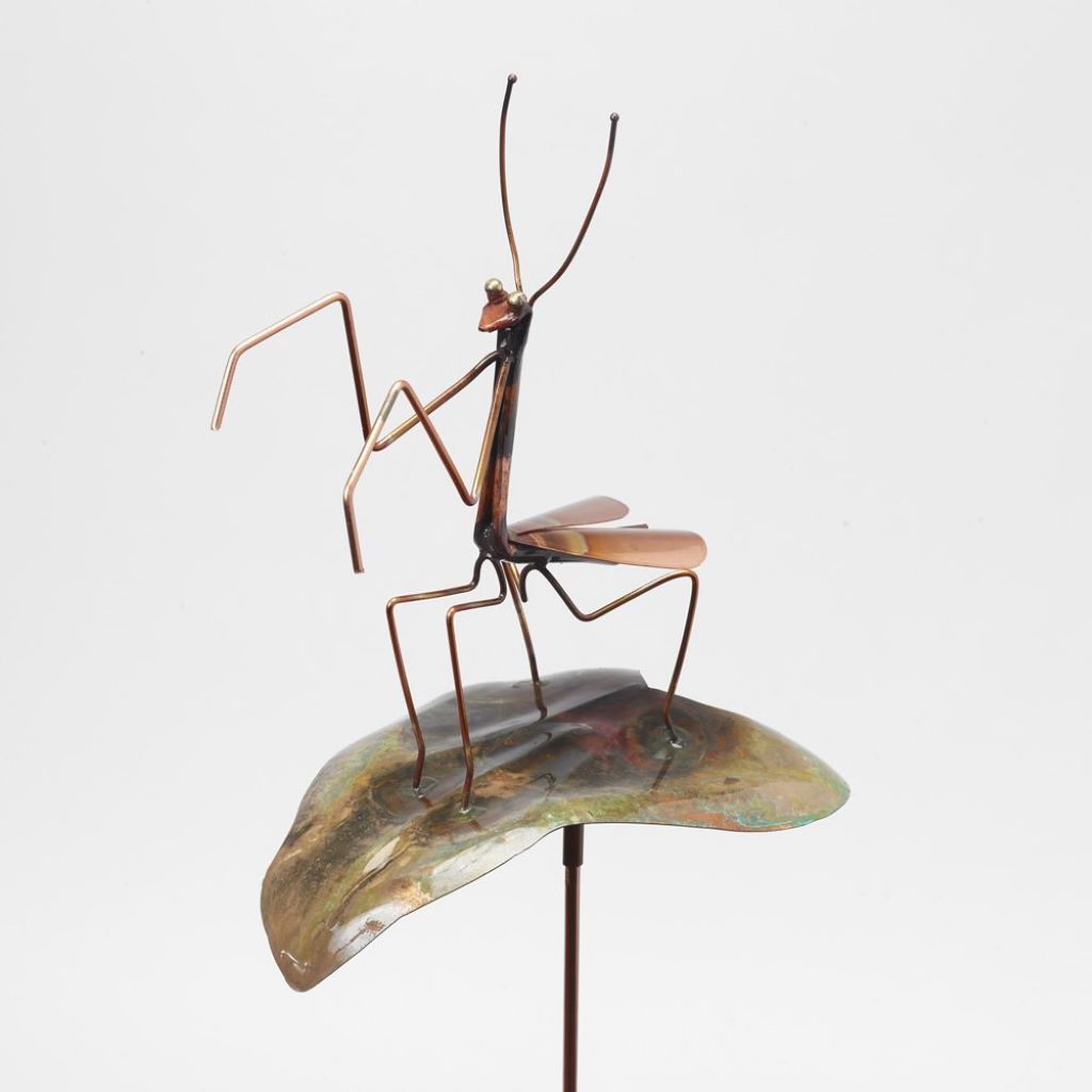 copper Praying Mantis sitting on leaf garden stake